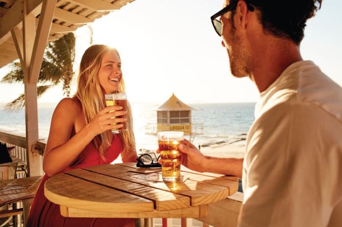 Couple enjoying a drink on the beach Tourism Queensland